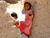 2 Afghan children waving to ISAF forces while they Barma a road